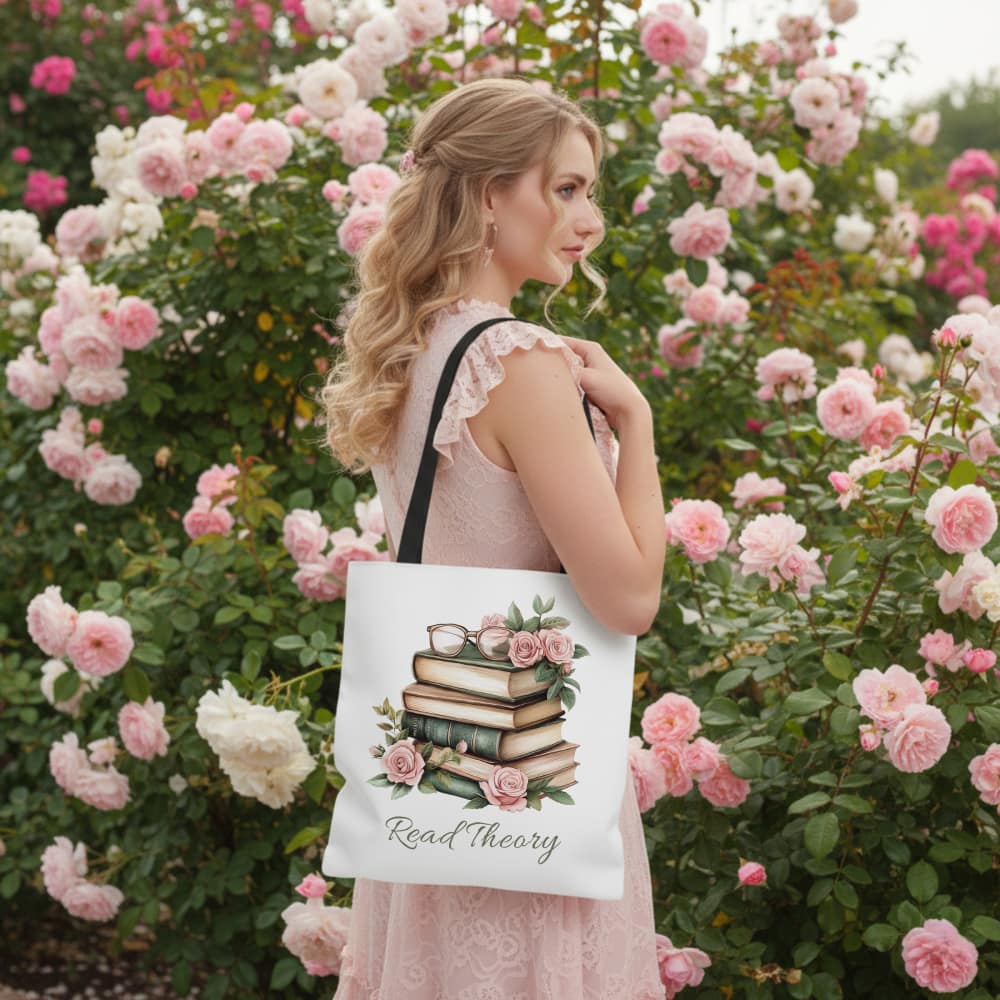 A woman in a pink dress stands in a lush garden of pink roses, carrying a tote bag with a stack of books and floral design that reads "Read Theory", evoking a serene, literary vibe.
